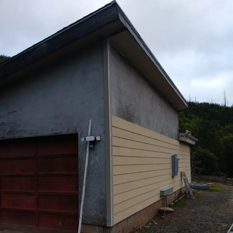 A detached garage halfway through new lap siding, the old siding still on one side