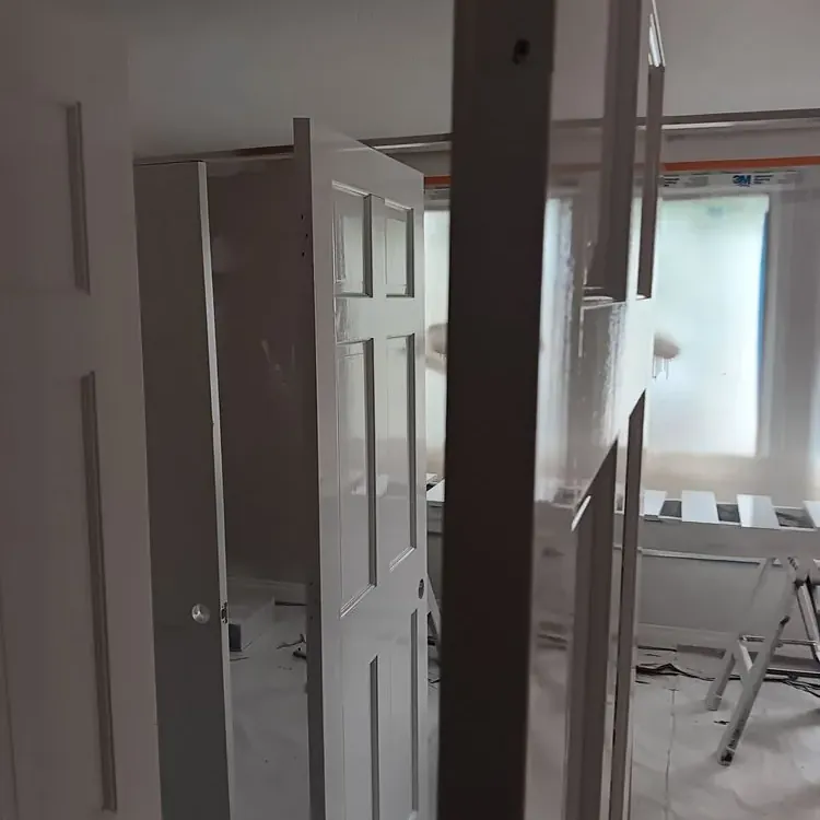 Interior doors and trim freshly painted white in a room covered in plastic sheeting