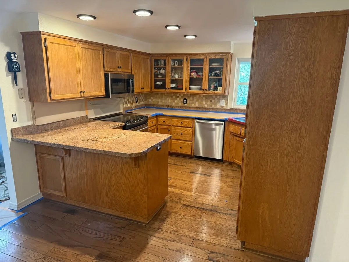 Before: a kitchen with honey oak cabinets, counters taped off