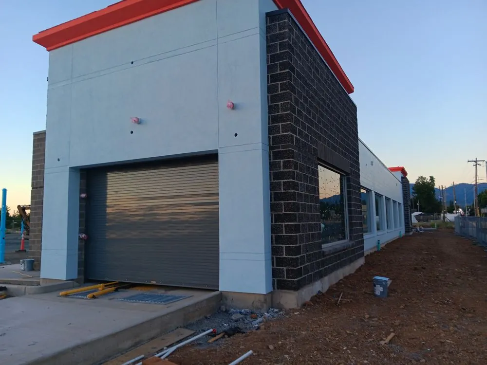 A commercial building with light grey walls and a roll-up door
