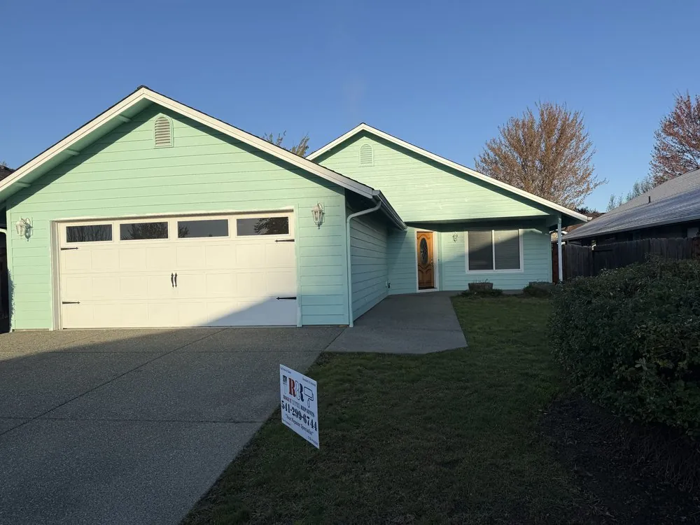 A single-story house repainted mint green, with a Rogue River Repaints yard sign on the lawn