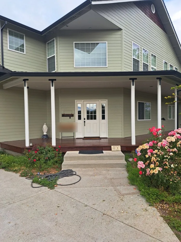 After: the same house repainted sage green, porch deck stained