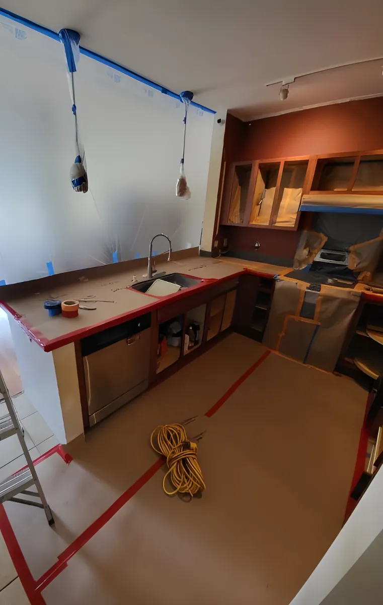 A kitchen masked off with tape and plastic before painting