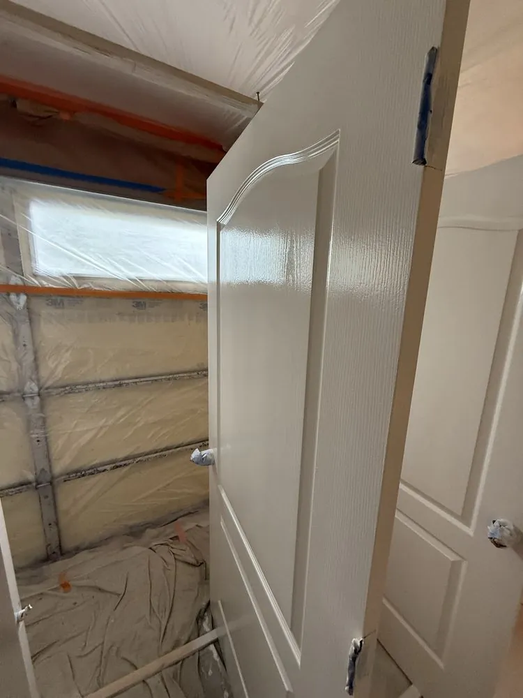 A room sealed floor to ceiling in plastic, a door freshly painted