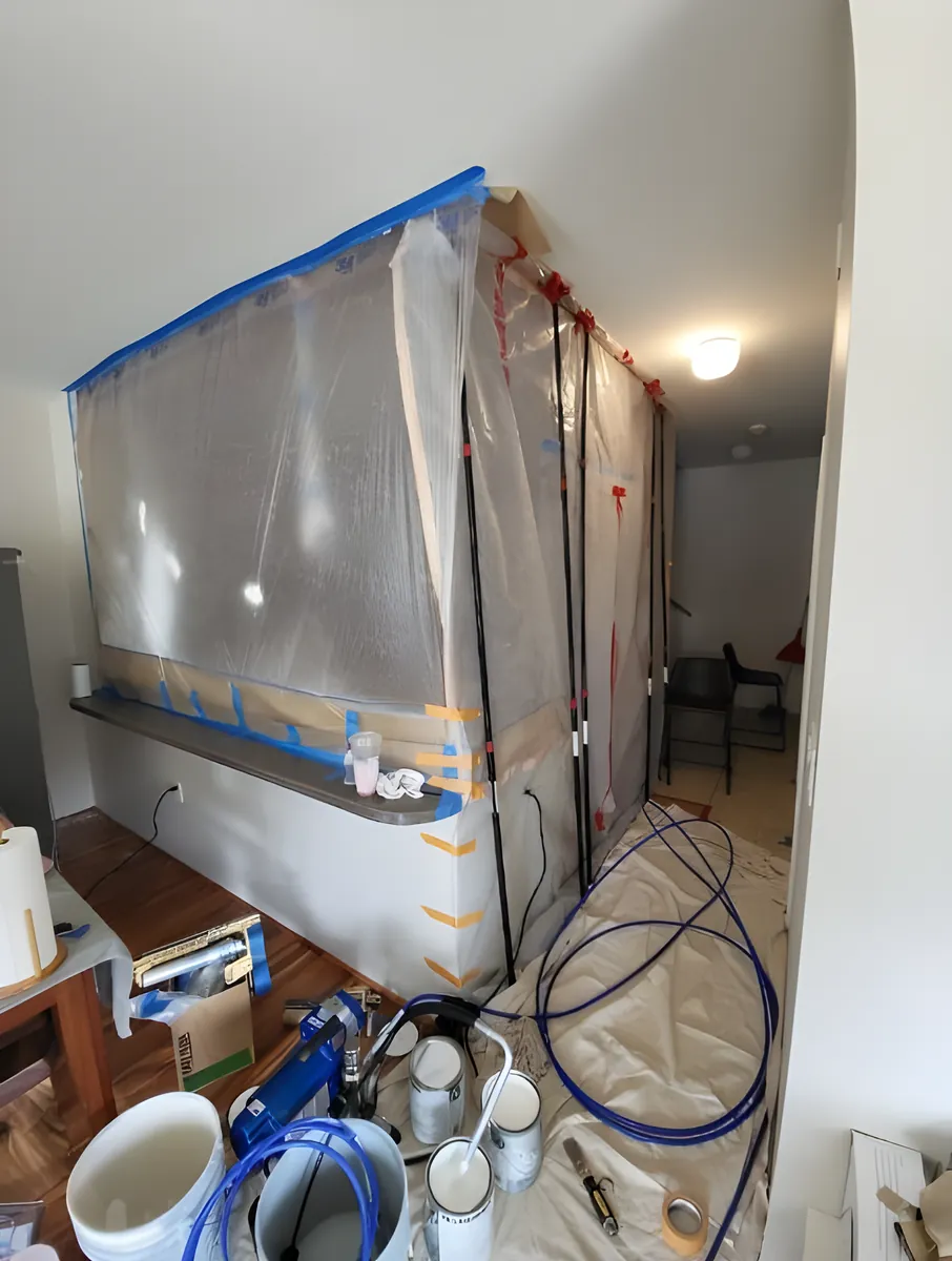 An interior wall sealed off in plastic sheeting and blue tape